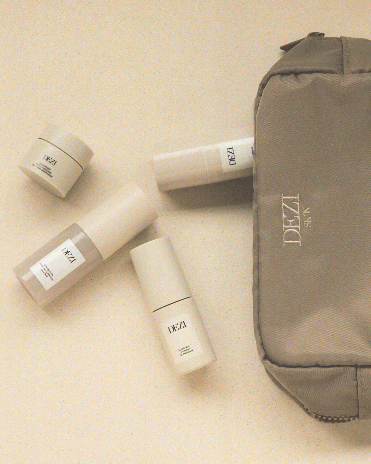 the cosmetic bag is laying on a surface and the four mini travel size skincare products are spilling out of it. 